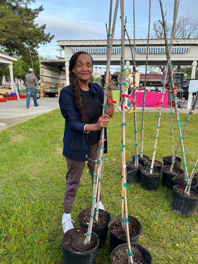 Woman holding tree at tree giveaway event.