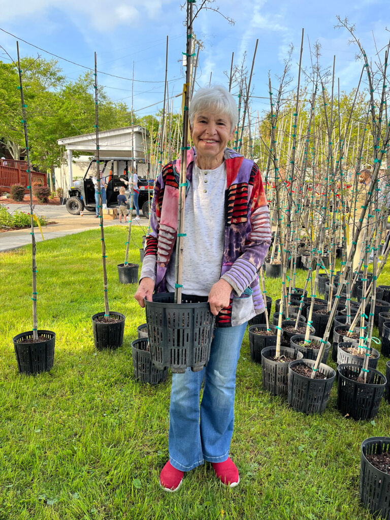 Woman holding tree at tree giveaway event.